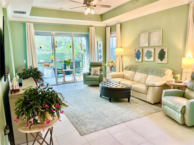 tiled living room with a raised ceiling, crown molding, and ceiling fan