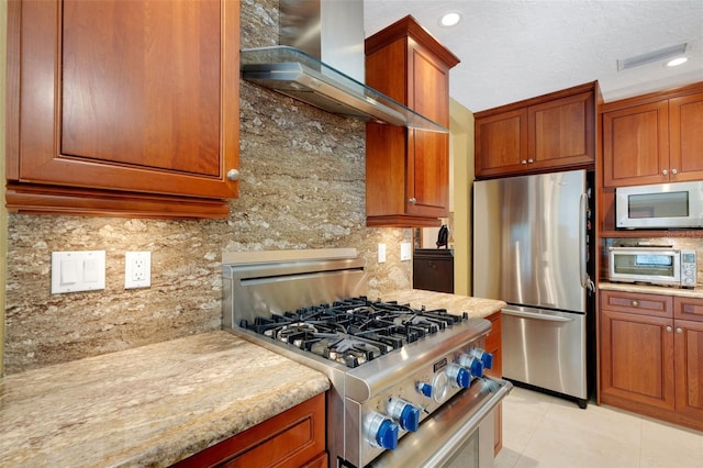 kitchen with light tile patterned flooring, range hood, tasteful backsplash, light stone counters, and stainless steel appliances