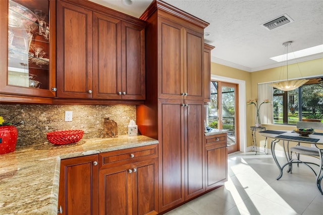 kitchen with tasteful backsplash, light stone counters, decorative light fixtures, a textured ceiling, and ornamental molding