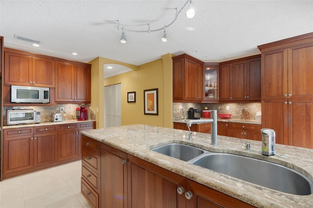 kitchen featuring backsplash, light stone countertops, sink, and light tile patterned floors