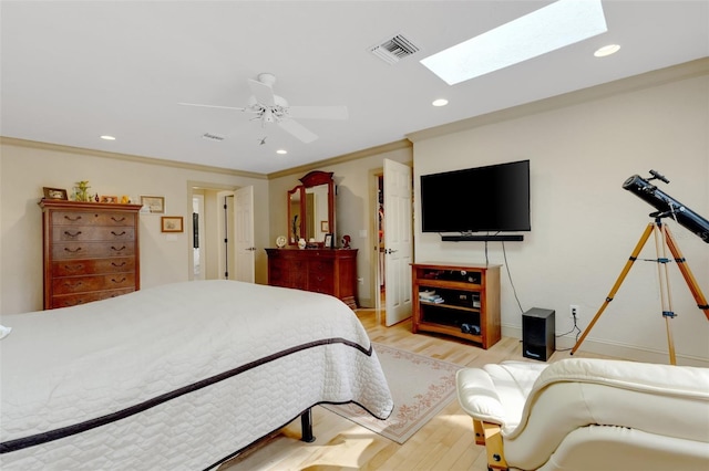 bedroom featuring a skylight, ornamental molding, ceiling fan, and light wood-type flooring