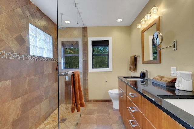 bathroom featuring vanity, tile patterned floors, toilet, and tiled shower