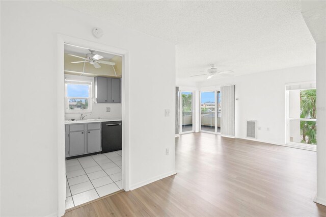 interior space featuring a textured ceiling, dishwasher, gray cabinetry, sink, and light hardwood / wood-style flooring