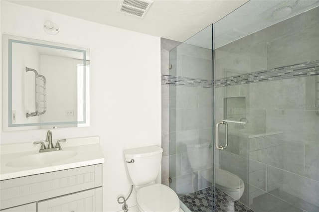 bathroom featuring toilet, a shower with shower door, and vanity