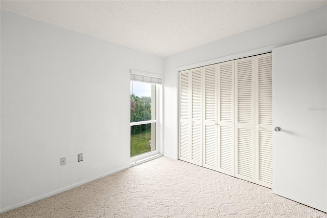 unfurnished bedroom with a closet, light colored carpet, and a textured ceiling