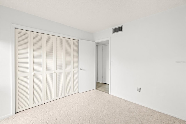 unfurnished bedroom featuring a closet and light carpet