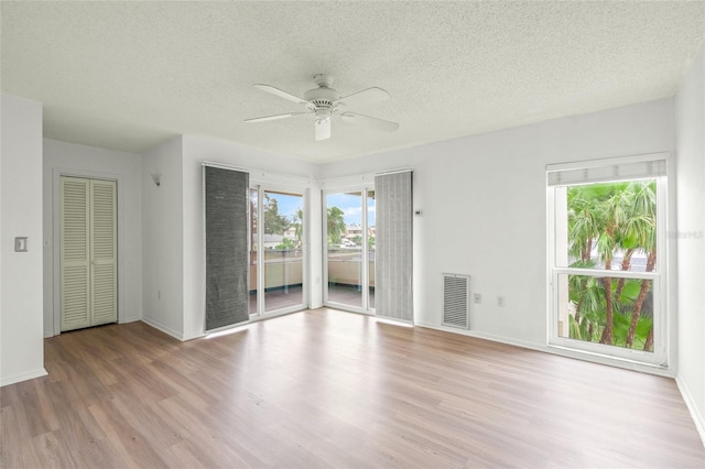 empty room featuring plenty of natural light, a textured ceiling, and light hardwood / wood-style flooring