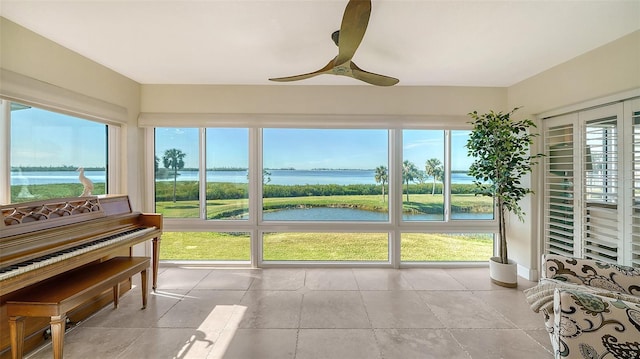 sunroom with a ceiling fan, a water view, and plenty of natural light