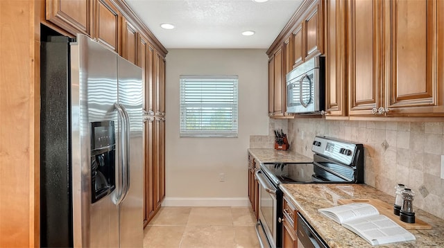 kitchen featuring appliances with stainless steel finishes, light tile patterned floors, backsplash, and light stone counters