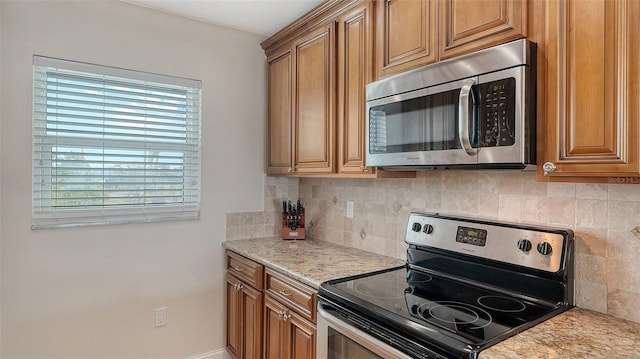 kitchen with tasteful backsplash, appliances with stainless steel finishes, and light stone countertops