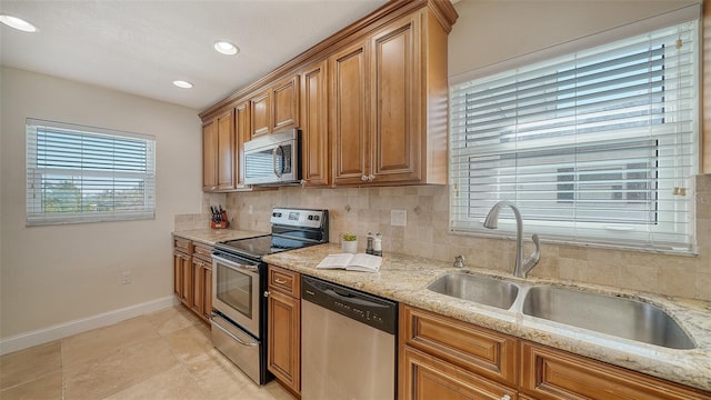 kitchen featuring stainless steel appliances, light stone countertops, sink, and decorative backsplash