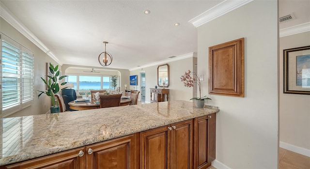 kitchen with crown molding, decorative light fixtures, light stone countertops, and light tile patterned floors