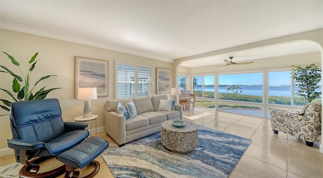 living room with ornamental molding, light tile patterned floors, ceiling fan, a water view, and a textured ceiling