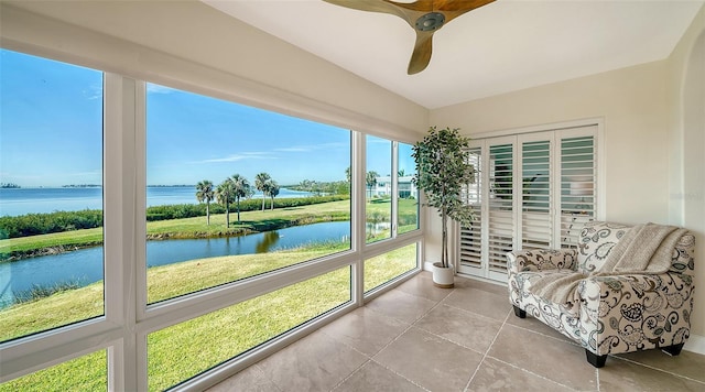 sunroom / solarium with ceiling fan and a water view