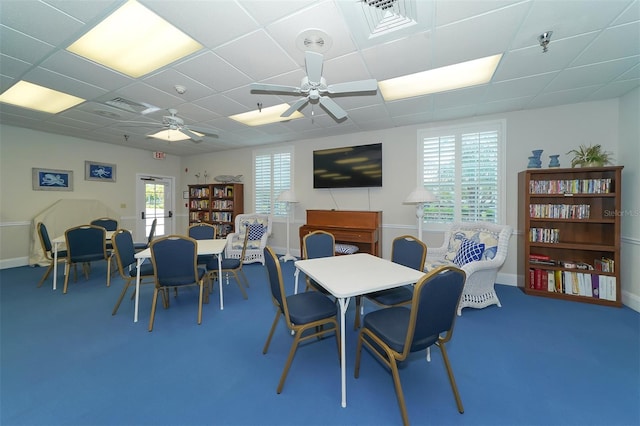 carpeted dining area with a paneled ceiling and ceiling fan