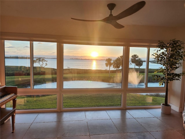 sunroom / solarium featuring ceiling fan, a water view, and a healthy amount of sunlight