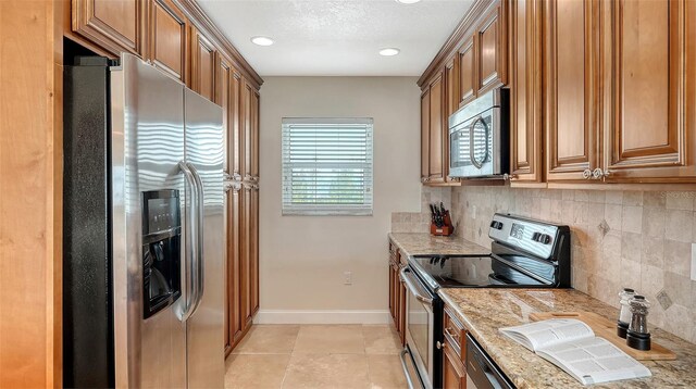 kitchen with stainless steel appliances, light stone counters, decorative backsplash, and brown cabinets