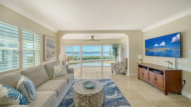 living area featuring light tile patterned floors, baseboards, arched walkways, and crown molding