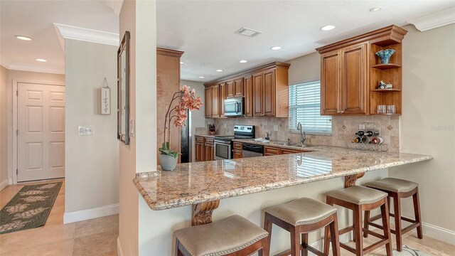 kitchen featuring open shelves, appliances with stainless steel finishes, light stone countertops, a peninsula, and a kitchen bar