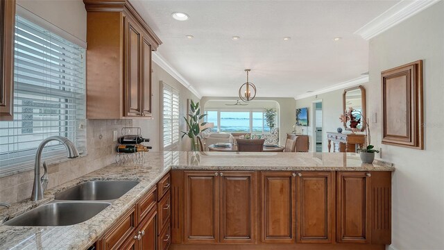 kitchen featuring a peninsula, brown cabinetry, and a sink