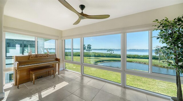 sunroom / solarium with a water view and a ceiling fan