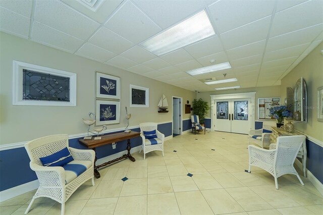 office featuring light tile patterned floors, baseboards, and a drop ceiling