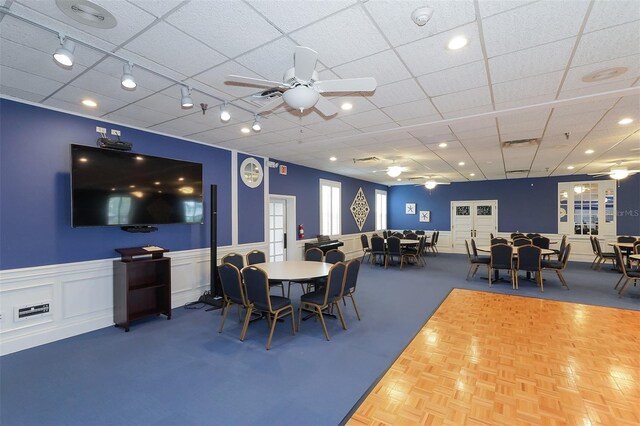 dining room featuring a ceiling fan, a wainscoted wall, a paneled ceiling, a decorative wall, and track lighting