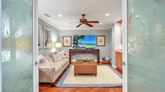 living room featuring ceiling fan, ornamental molding, and light hardwood / wood-style flooring