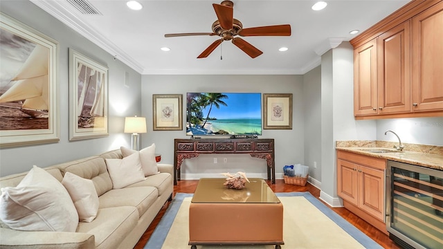 living room with ceiling fan, dark hardwood / wood-style floors, wet bar, wine cooler, and ornamental molding