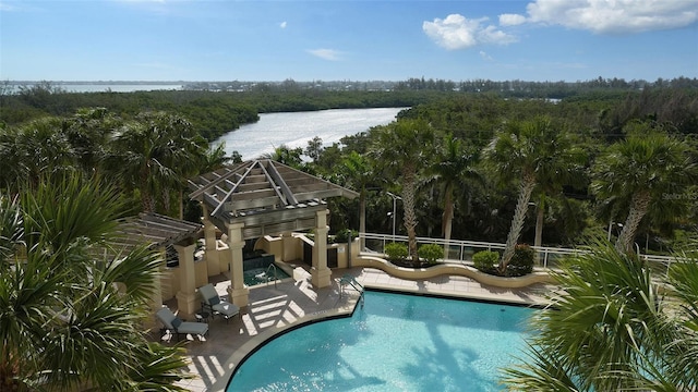 view of swimming pool with an outdoor structure, a water slide, a water view, and a patio