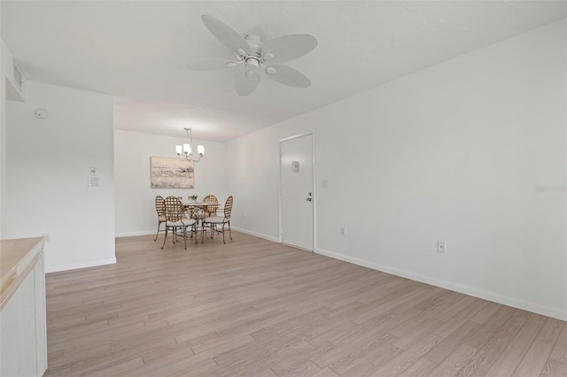 unfurnished dining area featuring light wood finished floors, baseboards, and ceiling fan with notable chandelier