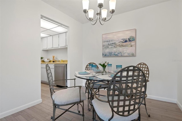 dining area featuring light wood-style floors, baseboards, and a chandelier