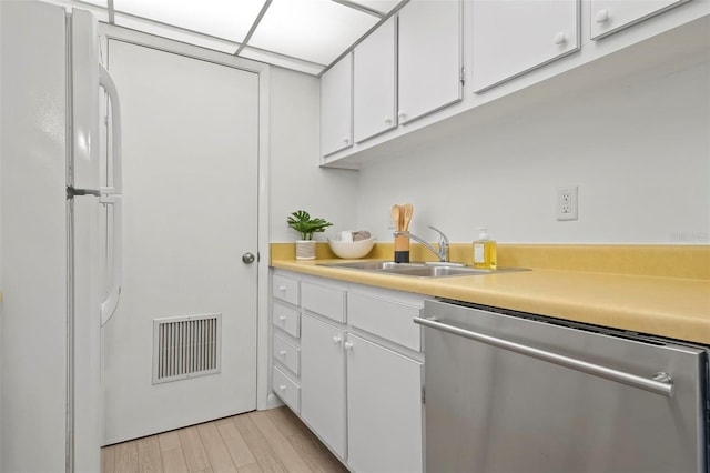 kitchen featuring light countertops, visible vents, freestanding refrigerator, white cabinetry, and dishwasher