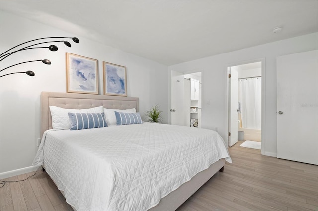 bedroom with light wood-style floors, connected bathroom, and baseboards