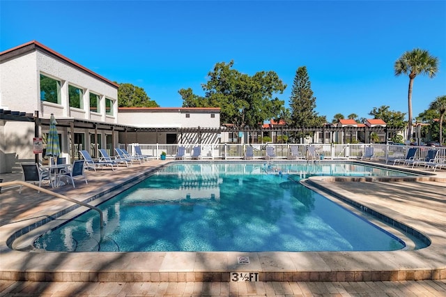 community pool with a patio area and fence