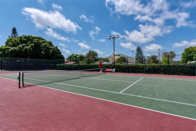 view of tennis court featuring community basketball court and fence