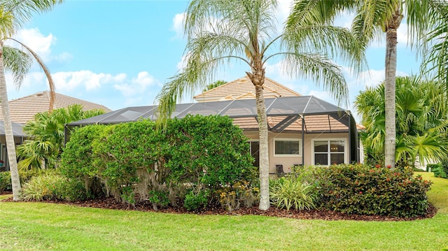 7244 Orchid Island Pl, Bradenton, FL 34202 - view of home's exterior with glass enclosure, a lawn, and stucco siding