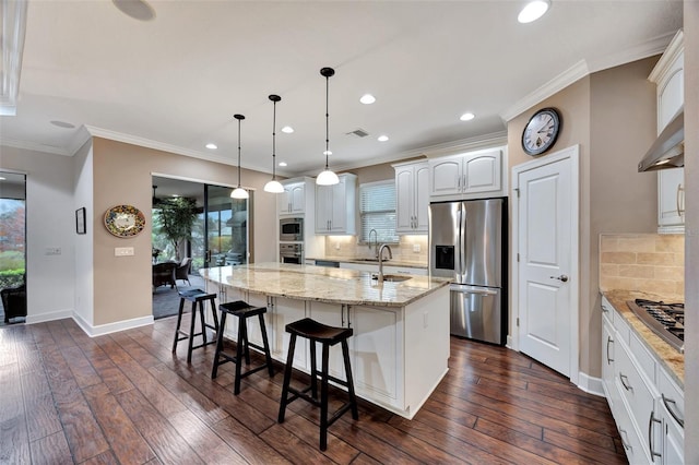 kitchen with pendant lighting, white cabinetry, a kitchen island with sink, stainless steel appliances, and light stone countertops