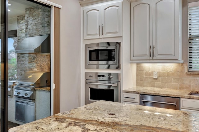 kitchen featuring tasteful backsplash, light stone countertops, stainless steel appliances, and white cabinets