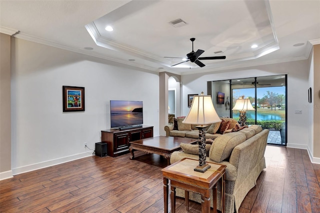 living room with dark hardwood / wood-style flooring, ornamental molding, a raised ceiling, and ceiling fan