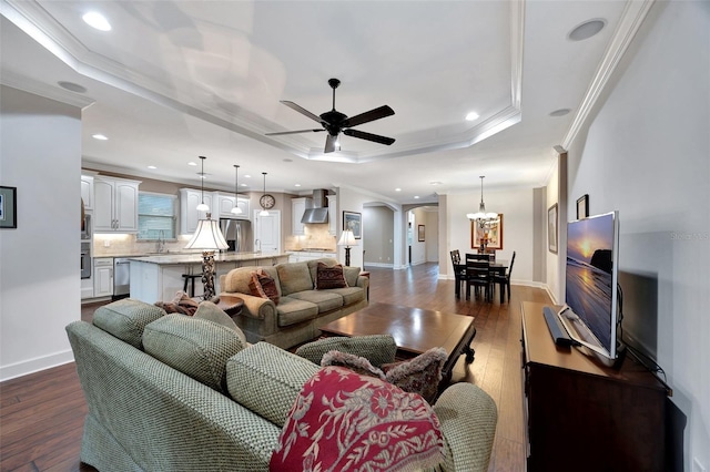 living room featuring dark wood-type flooring, sink, ceiling fan, and a tray ceiling