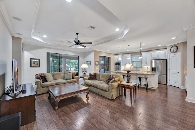 living room featuring sink, a tray ceiling, ornamental molding, and dark hardwood / wood-style floors