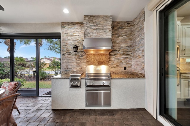 kitchen with stone counters and wall chimney exhaust hood