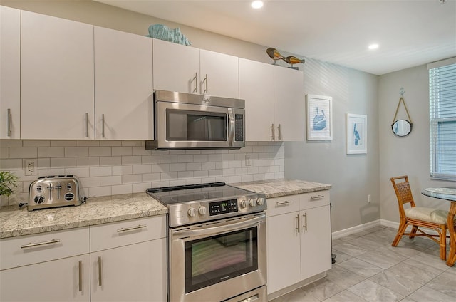 kitchen featuring light stone counters, stainless steel appliances, tasteful backsplash, and white cabinets