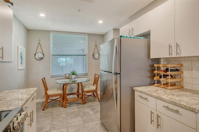 kitchen with light stone counters, decorative backsplash, white cabinets, and appliances with stainless steel finishes