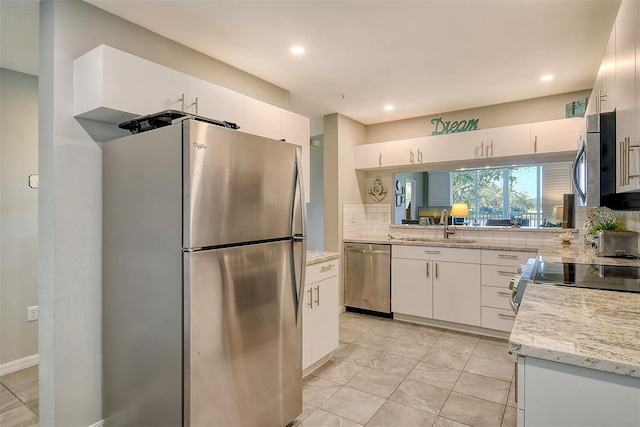 kitchen featuring sink, white cabinetry, stainless steel appliances, light stone countertops, and backsplash