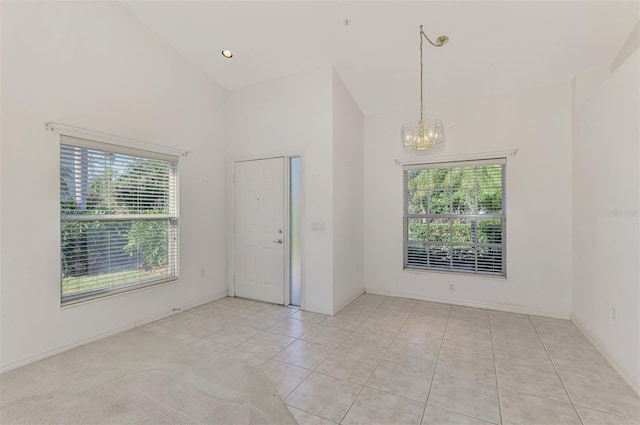 tiled spare room with an inviting chandelier and high vaulted ceiling