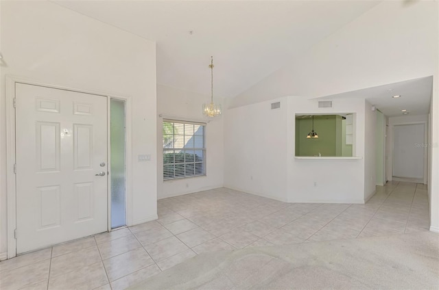 tiled entryway with high vaulted ceiling and a chandelier