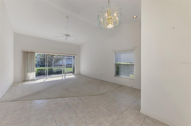 carpeted spare room featuring ceiling fan with notable chandelier, plenty of natural light, and high vaulted ceiling