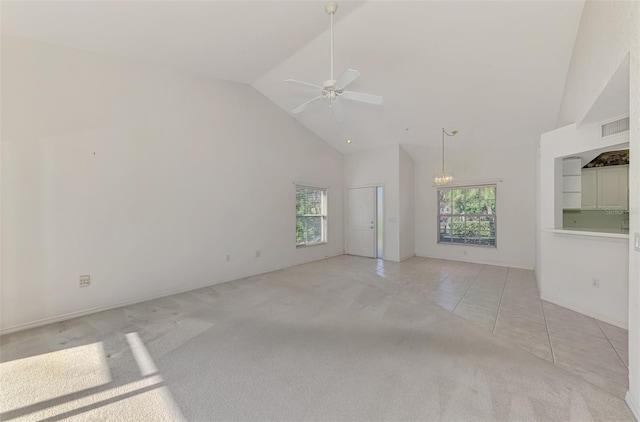 carpeted empty room with ceiling fan with notable chandelier and high vaulted ceiling